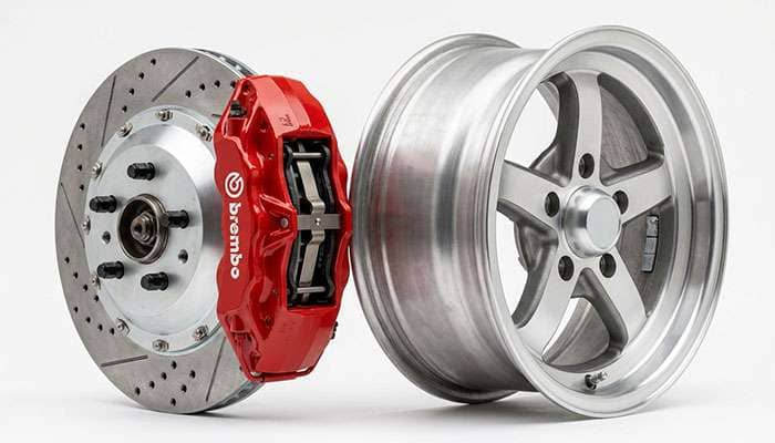 Brake rotor and caliper assembly positioned next to a classic car wheel showing the clearance gap between caliper and wheel barrel