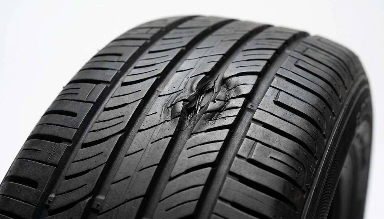 close-up of a radial tire tread showing a raised high spot and distorted tread blocks caused by internal steel belt separation