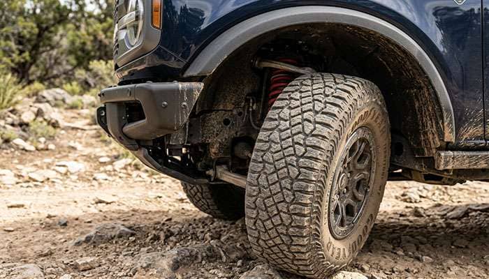 Front tire of a Ford Bronco turned to full lock next to the steel crash bar behind the end of the front bumper