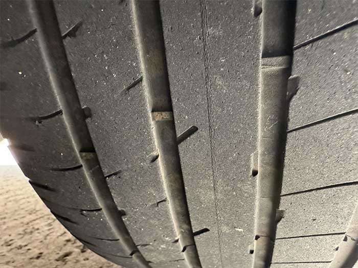 Close-up of a Tesla Model Y tire showing severe tread wear after only 10,000 miles of use