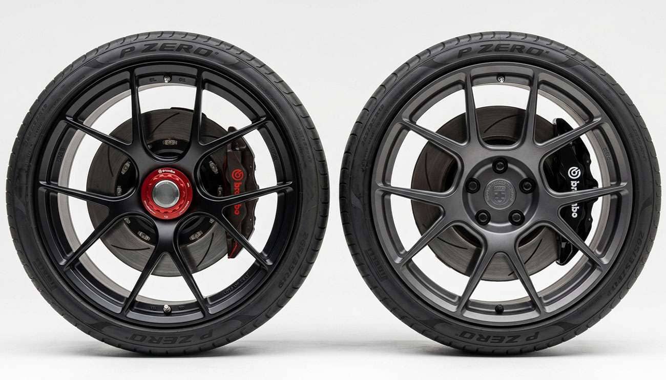 A centerlock wheel with a single central nut next to a lug-mount wheel with five lug nuts on a clean white studio background