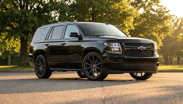 Black 2020 Chevrolet Tahoe with custom black Niche VOSSO wheels parked on pavement near trees