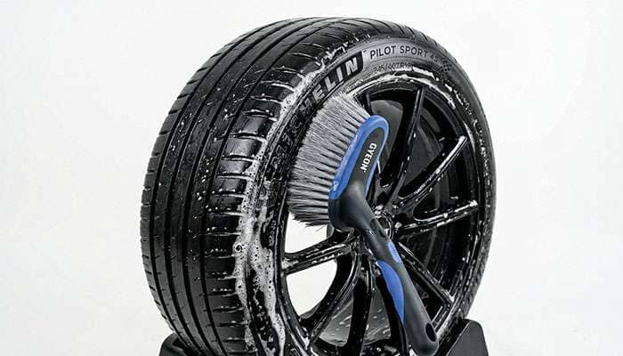 Tire being cleaned with a soft brush and soapy water