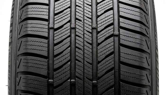 Close-up of Continental TrueContact Tour 54 tread showing twin center ribs, circumferential grooves, and dense siping