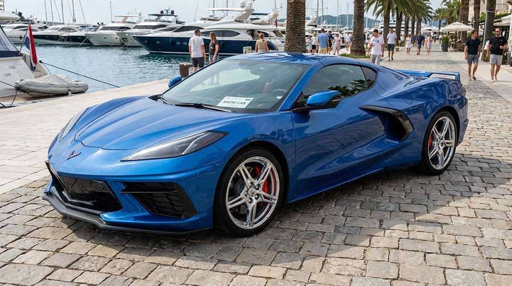 Blue Corvette E-Ray convertible with chrome wheels and red brake calipers at marina showcasing show car wheel finish