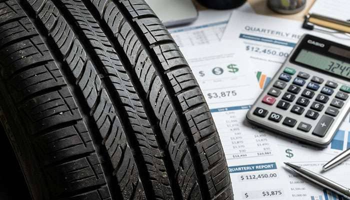 Tire tread surface with dollar value calculation concept overlay showing cost per mile economics