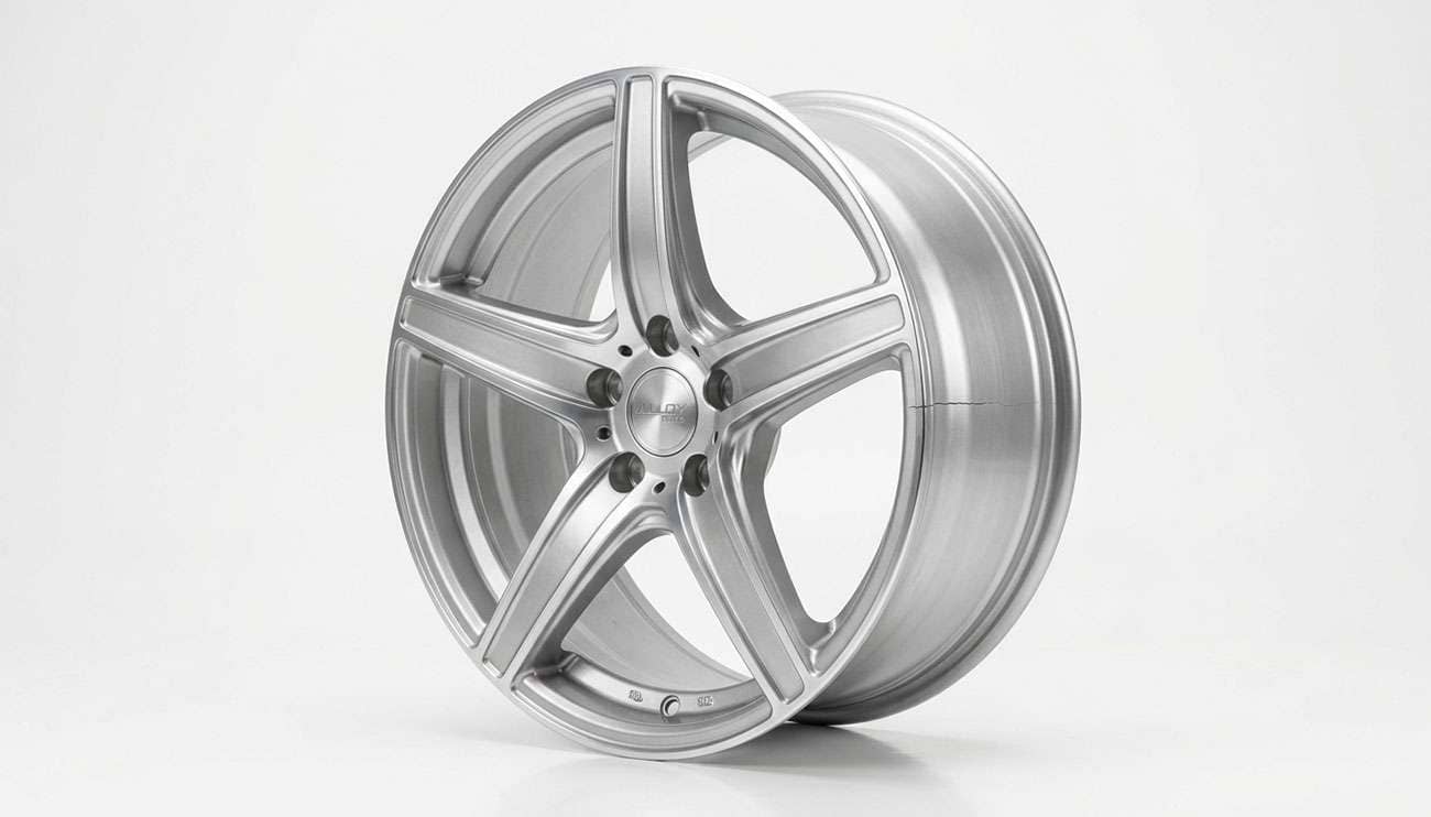 Cracked alloy wheel removed from a vehicle and set on a clean white backdrop for inspection