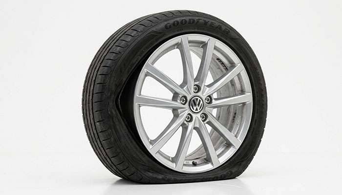Aluminum alloy wheel with the tire partially unseated from the bead flange after air loss through a cracked rim