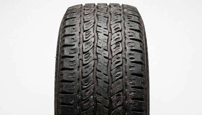 close-up of a tire tread showing a scalloped cupping wear pattern with alternating high and low sections around the circumference
