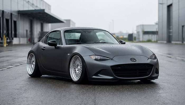 Dark gray ND Miata with lowered stance and polished three-piece mesh wheels parked on asphalt