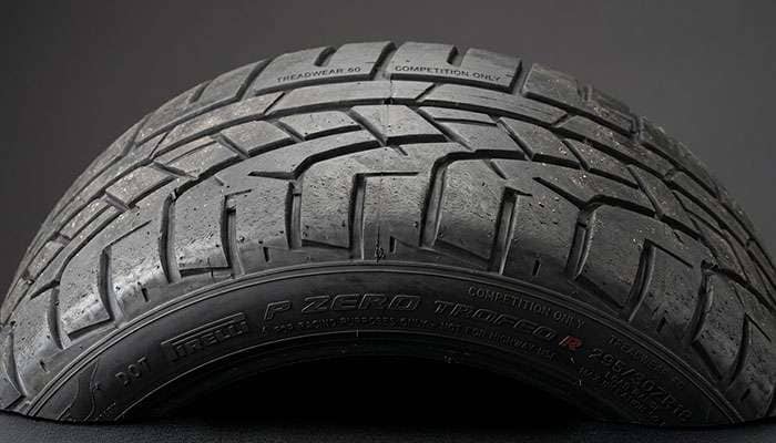 Close-up of a DOT race tire shoulder showing aggressive tread blocks and minimal void area engineered for maximum grip