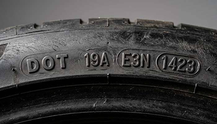 Close-up of a DOT tire date code stamped into the tire sidewall with the last four digits showing manufacture week and year