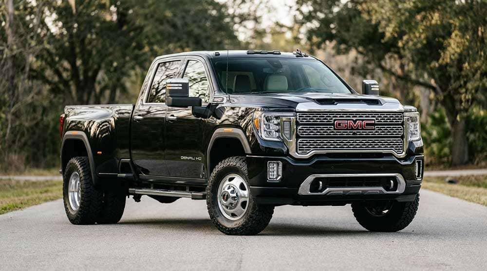 Black GMC Sierra 3500 Denali HD dually pickup truck parked on a road with trees in the background