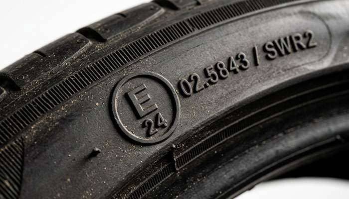 Close-up of a circled E-mark approval stamp molded into a tyre sidewall