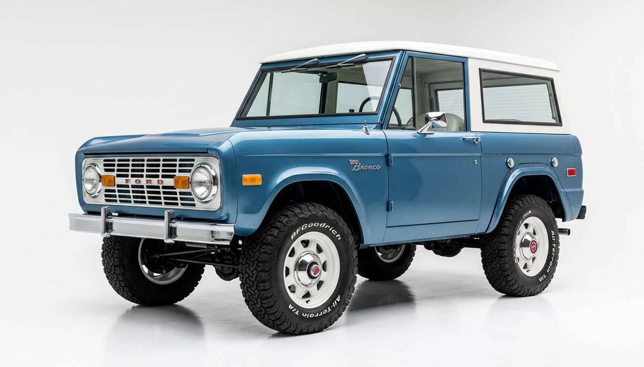 First-generation Ford Bronco on classic white eight-spoke wheels and all-terrain tires in a studio