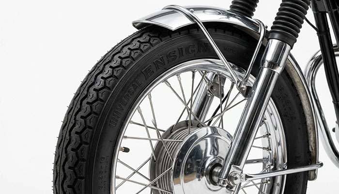 Ensign Universal 3.25-19 tire with raised ENSIGN lettering on the narrow 19-inch spoked front wheel of a 1960s British-style twin