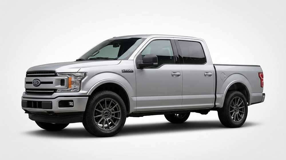 Silver 2021 Ford F-150 pickup truck parked on a residential driveway with aftermarket wheels and tires