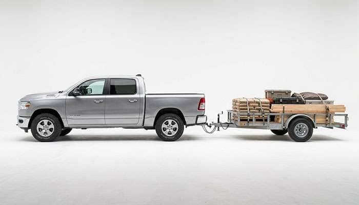 Half-ton pickup truck on Falken Wildpeak A/T4W tires towing a loaded utility trailer on a highway
