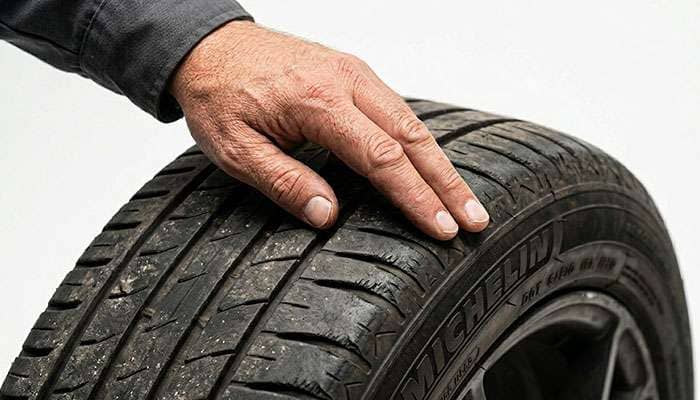 Running a hand across tire tread to feel the sharp and rounded edges of feathering