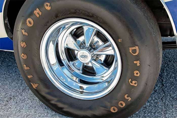 Close-up of a Firestone Drag 500 tire mounted on a shiny Cragar S/S chrome wheel on a classic car
