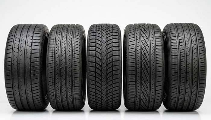 A lineup of five different car tires showcasing various tread patterns and designs on a white background.