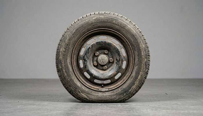 Flat-spotted car tire showing deformation from long-term garage storage on concrete