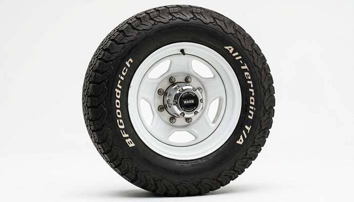 1970s Ford 4x4 pickup front wheel showing a manual locking hub through the center of a white spoke wheel