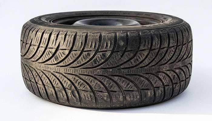 Rear tire from a front-wheel drive car showing diagonal and cupped wear patches across the tread