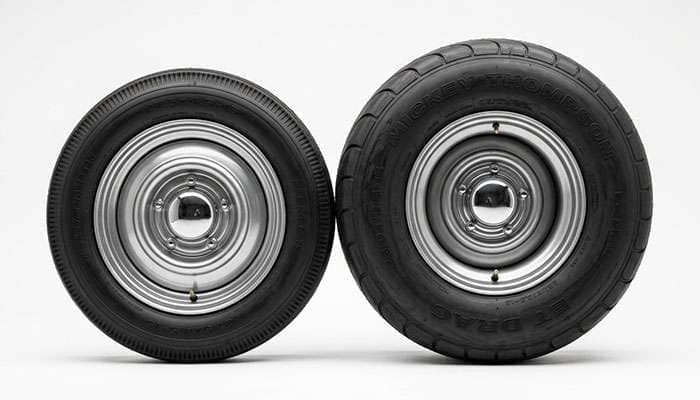 Big-and-little gasser wheel and tire setup with narrow front runner and wide rear drag tire shown side by side on a clean white studio backdrop