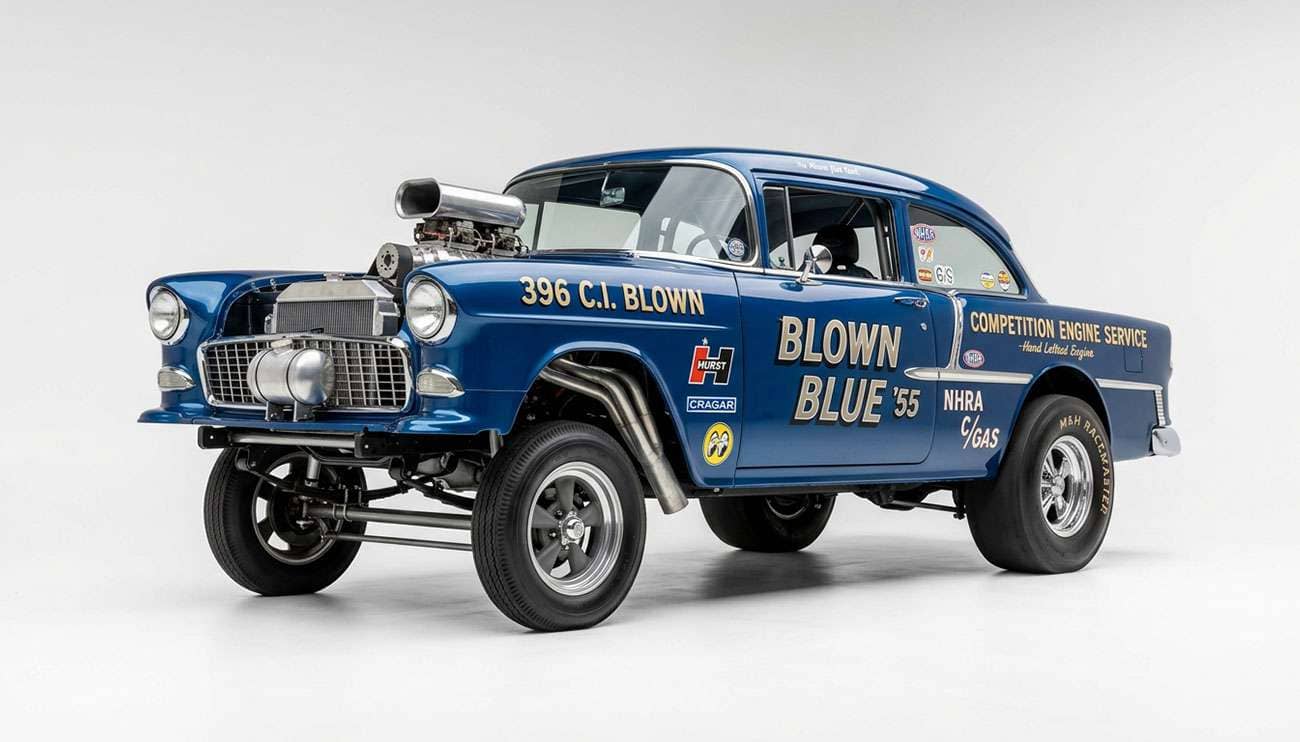 Classic 1955 Chevy gasser with raised straight-axle front end, skinny front runner tires, and wide rear drag tires on a white studio backdrop