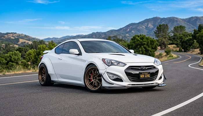 White Genesis Coupe with wide-body kit and custom bronze wheels parked on road under a blue sky with fitment guide text above