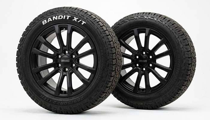 Close-up of two black 22' Yukon rims with 285/50r22 Bandit X/T tires for GMC Sierra and Chevy trucks.