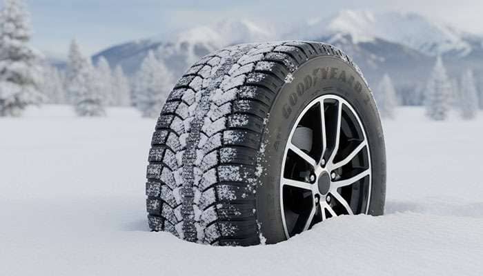Close-up of a Goodyear WeatherReady 2 winter tire with snow on the tread and rim during snowy conditions