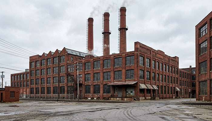 Historic red brick tire factory buildings with tall smokestacks in an old Ohio industrial district