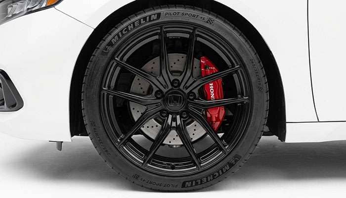 Close-up of a dark gray 2017-2021 Honda Accord front wheel with aftermarket black multi-spoke rims in a parking lot