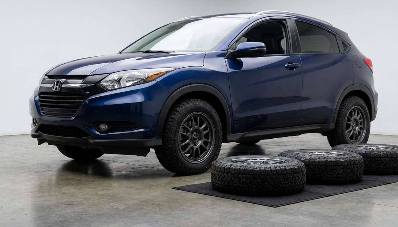 Close-up of a blue Honda HR-V with aftermarket tires and three spare tires on the floor in front of it