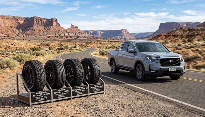 Four different tire models displayed beside a Honda Ridgeline driving on a desert road promoting best tires for performance and safety.