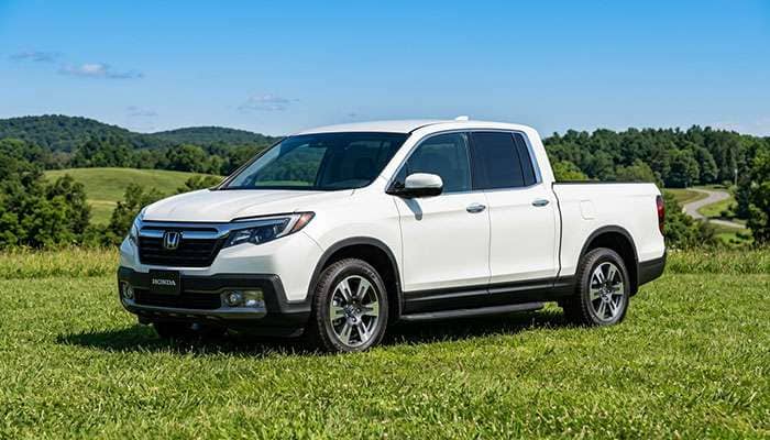 White Honda Ridgeline pickup truck parked on grass under clear blue sky with 'Fresh Kicks for the Ridgeline' text.