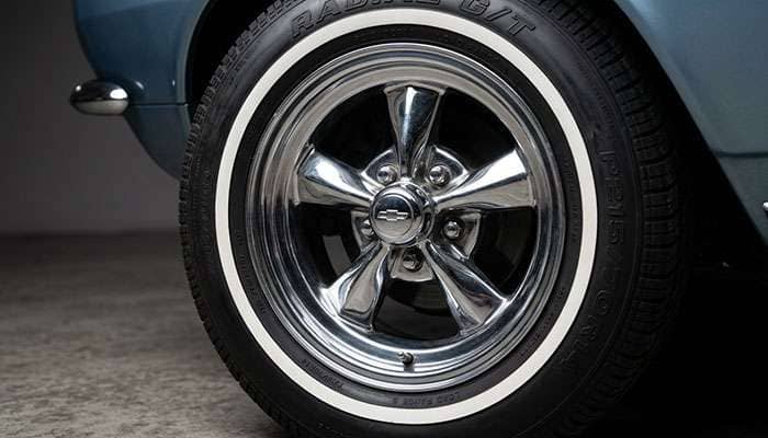 Classic chrome polished mag wheel with whitewall radial tire detail showing street rod aesthetic