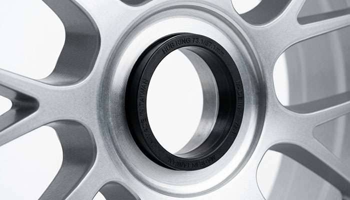 Close-up detail of a plastic hub-centric ring installed inside an aftermarket wheel center bore showing how it fills the gap between the wheel and the vehicle hub