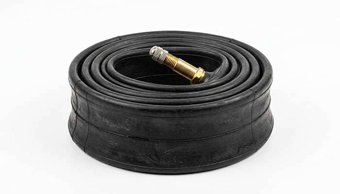 Classic car inner tube coiled with valve stem visible on a clean white studio backdrop