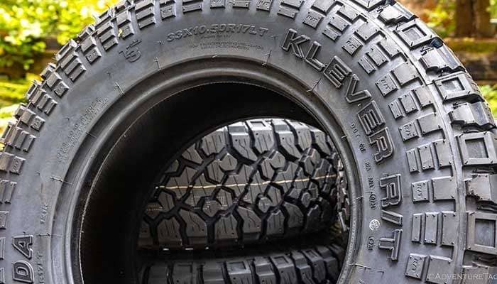 Close-up of Kenda Klever RT off-road tires stacked outdoors with detailed tread patterns visible