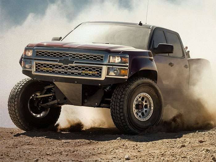 Off-road pickup truck kicking up dust, showcasing rugged KMC Wheels and aggressive tire tread on rough terrain