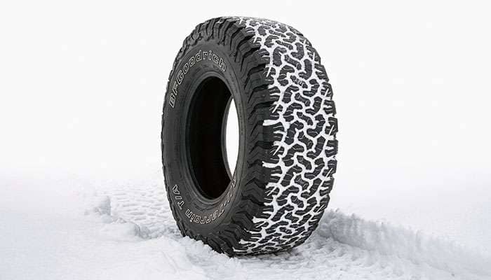 BFGoodrich KO3 all-terrain tire driving through packed snow on a rural road