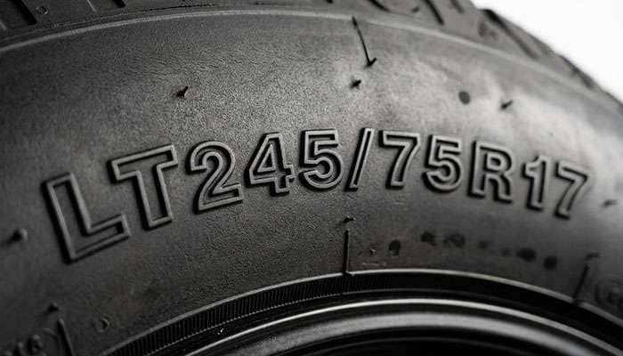Close-up of a light truck tire sidewall showing the LT prefix ahead of the tire size marking on a clean white seamless backdrop