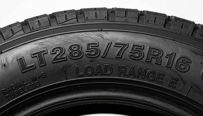 Close-up of LT tire sidewall showing the LT designation size and load range stamping