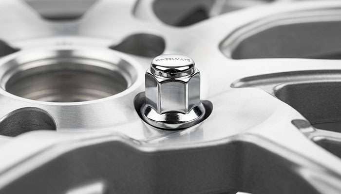 Close-up of a conical lug nut seated in a wheel lug hole showing the tapered contact surface