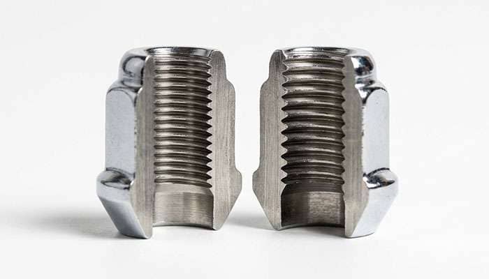 Two lug nuts shown side by side in cutaway view with visibly different thread spacing on their internal threads