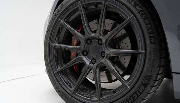 Matte black wheel close-up showing how the finish conceals brake dust on a clean white studio backdrop