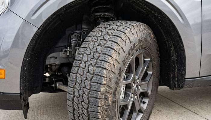 Front wheel of a compact unibody pickup turned to full lock showing tire clearance to the plastic fender liner and pinch weld